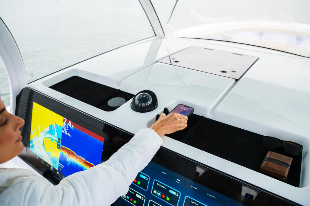 Captain operating boat electronics and holding phone near wireless charger at helm station