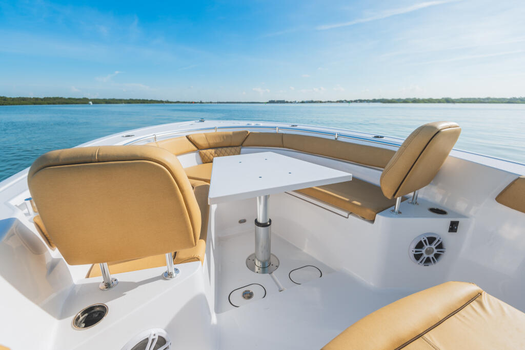 Spacious bow seating area with tan cushioned seats and white table aboard a center console boat
