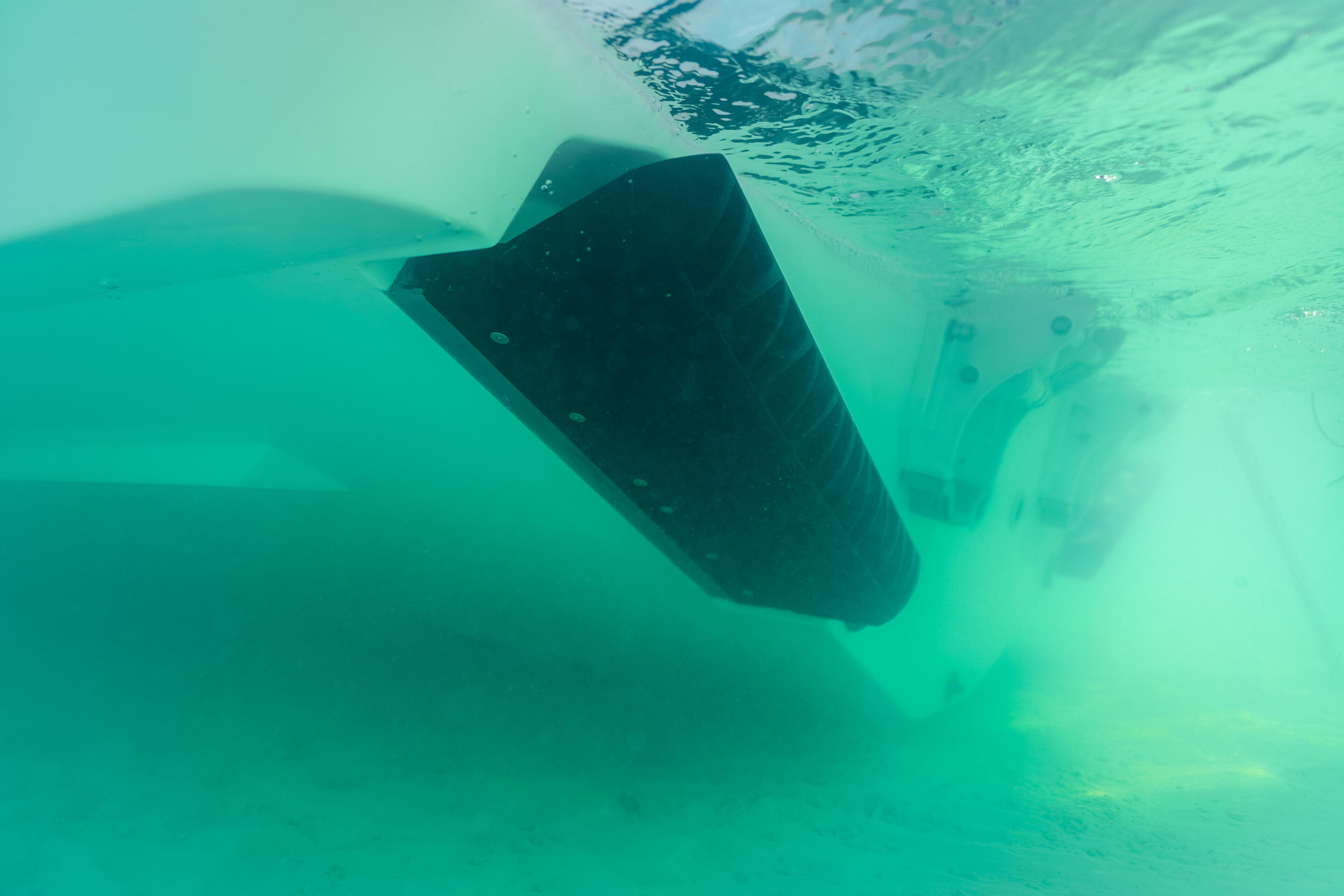 Underwater view of boat hull and running gear in clear turquoise water at sandbar