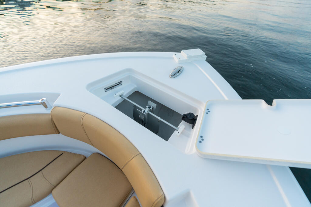 Center console bow with tan cushioned seating and open storage locker on calm water