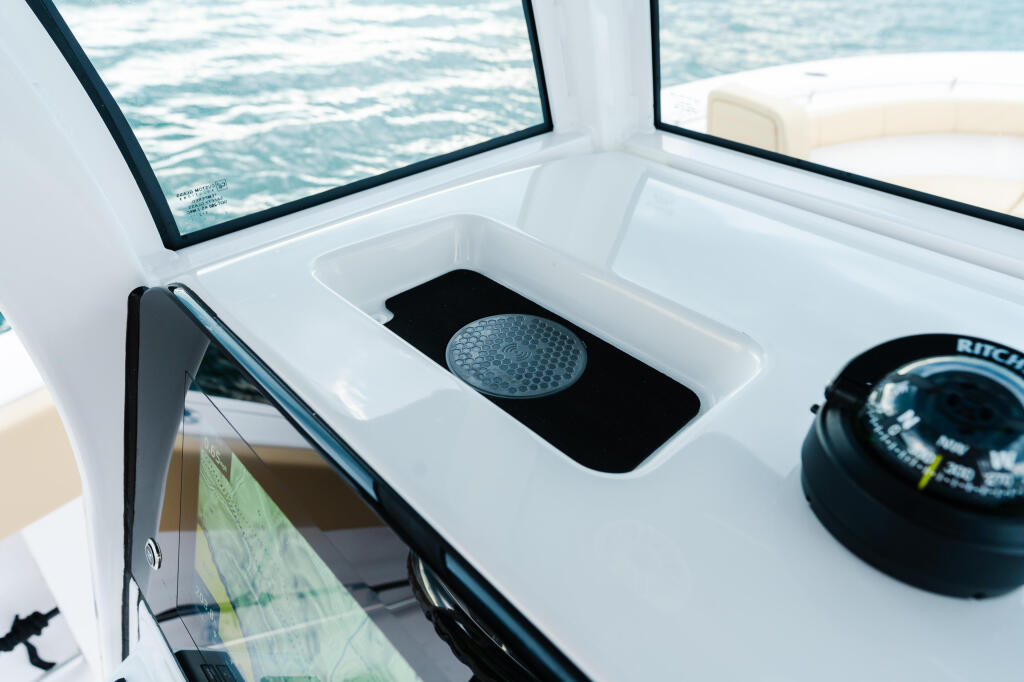 Helm area with windshield, compass, and storage compartment overlooking open water
