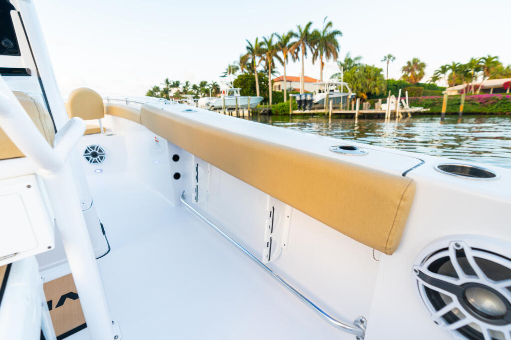 Starboard gunwale and cushioned seating of center console cockpit overlooking marina with palm trees
