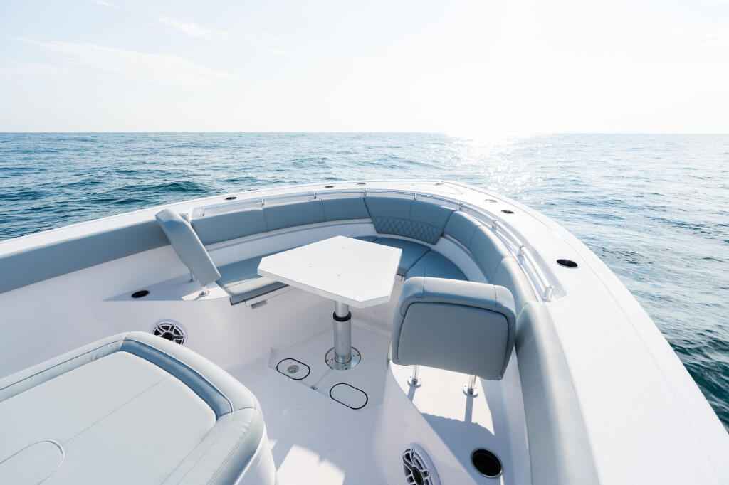 Spacious helm seating area in bow of white center console boat with table and calm ocean ahead