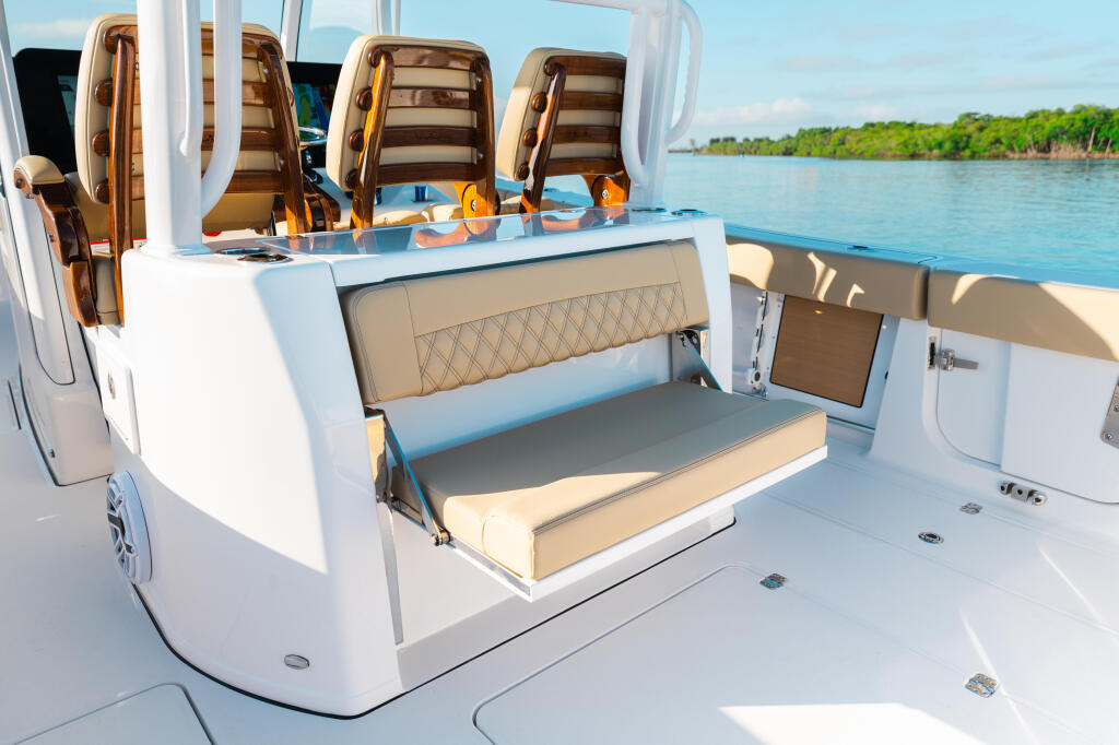 Spacious sun deck with upholstered seating, storage compartments, and helm controls on a modern center console boat