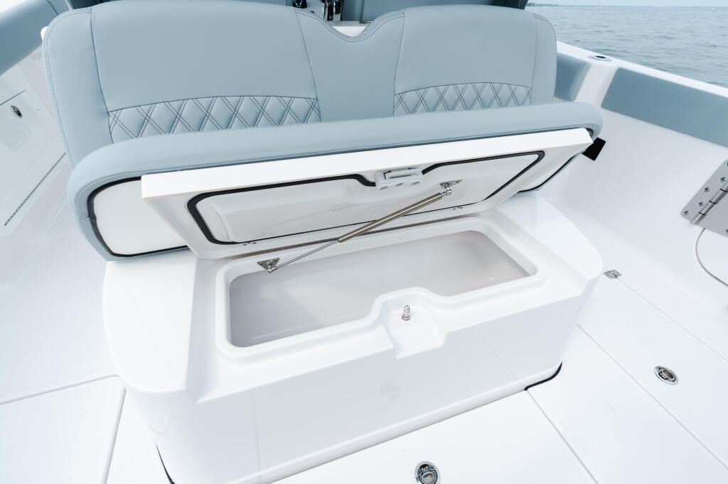Open cooler and quilted gray seating in the boat's cockpit with ocean visible beyond