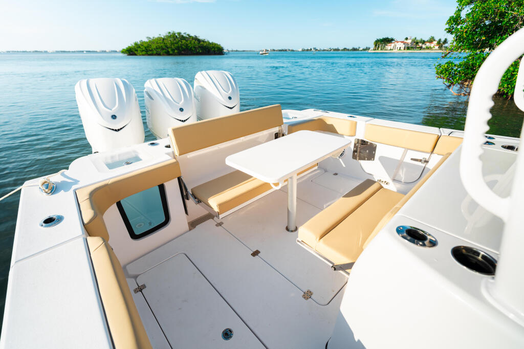 Open 352 center console boat with white cushioned seating and tan upholstery moored in tropical turquoise waters