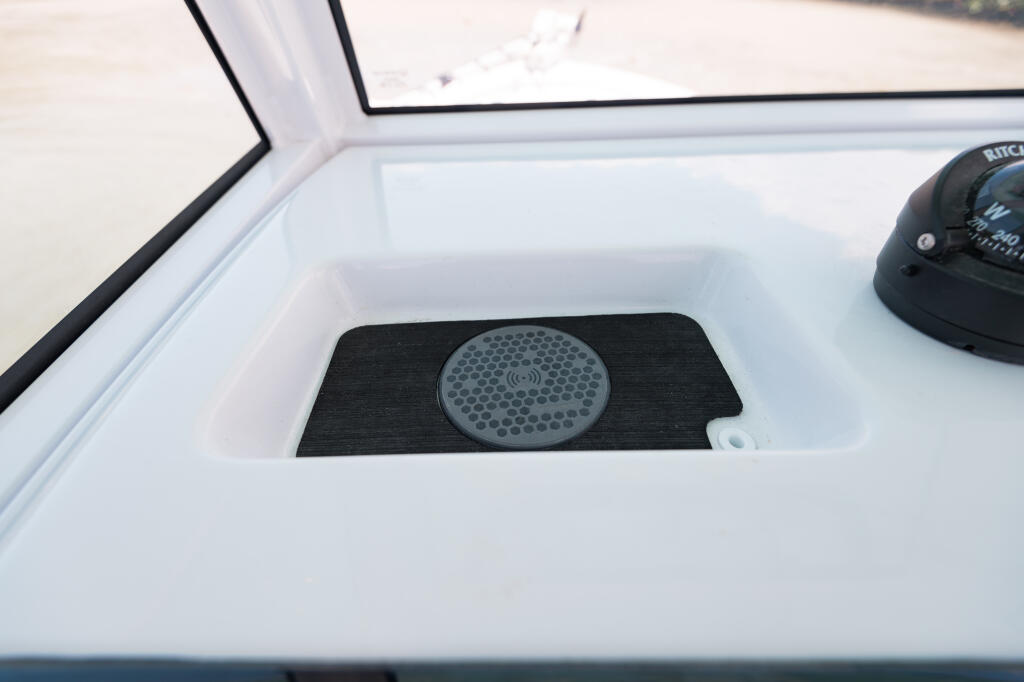 Wireless phone charger with speaker grille mounted in boat console