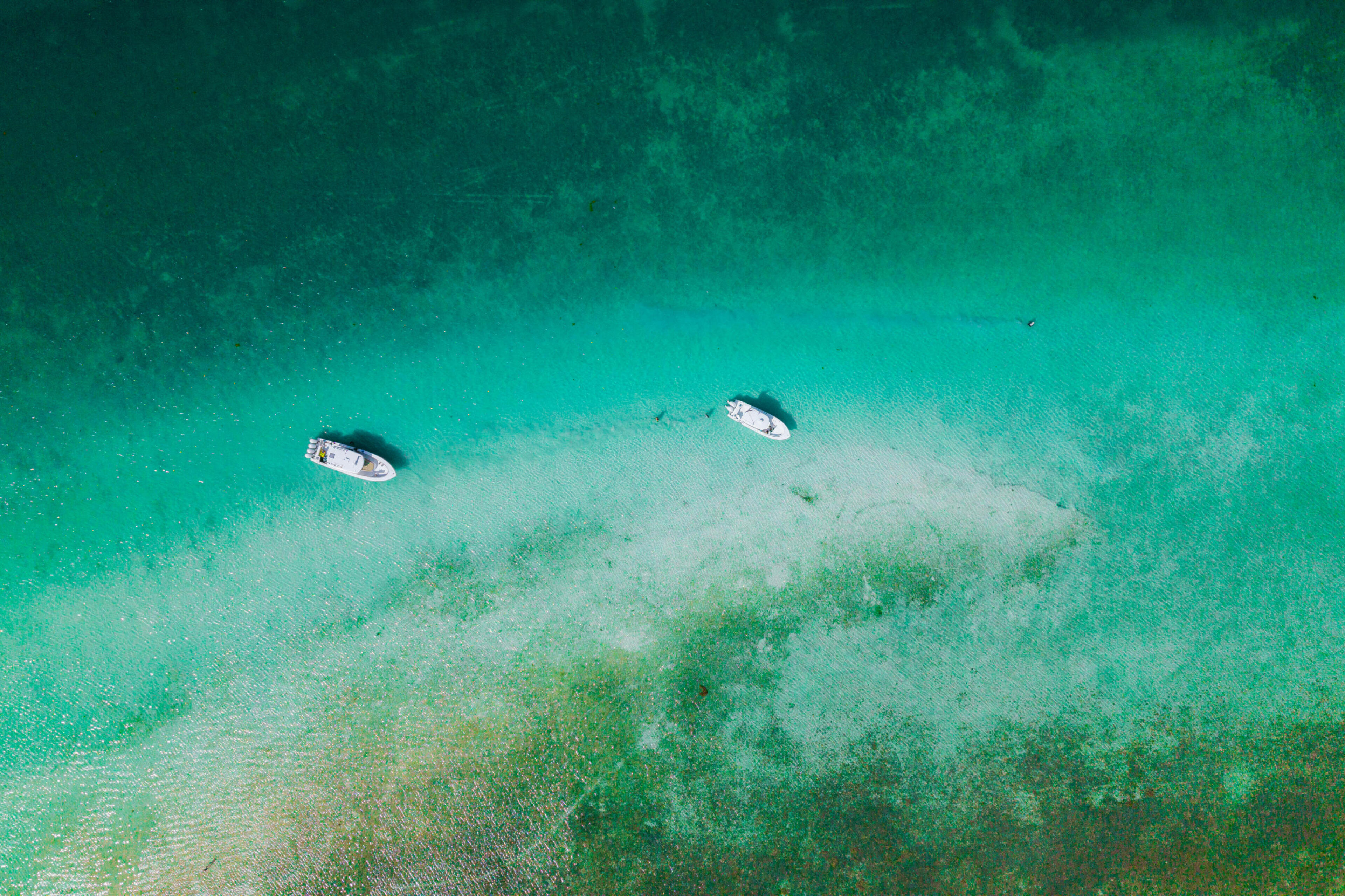 Two boats anchored in shallow turquoise water over a sandy bottom in Islamorada