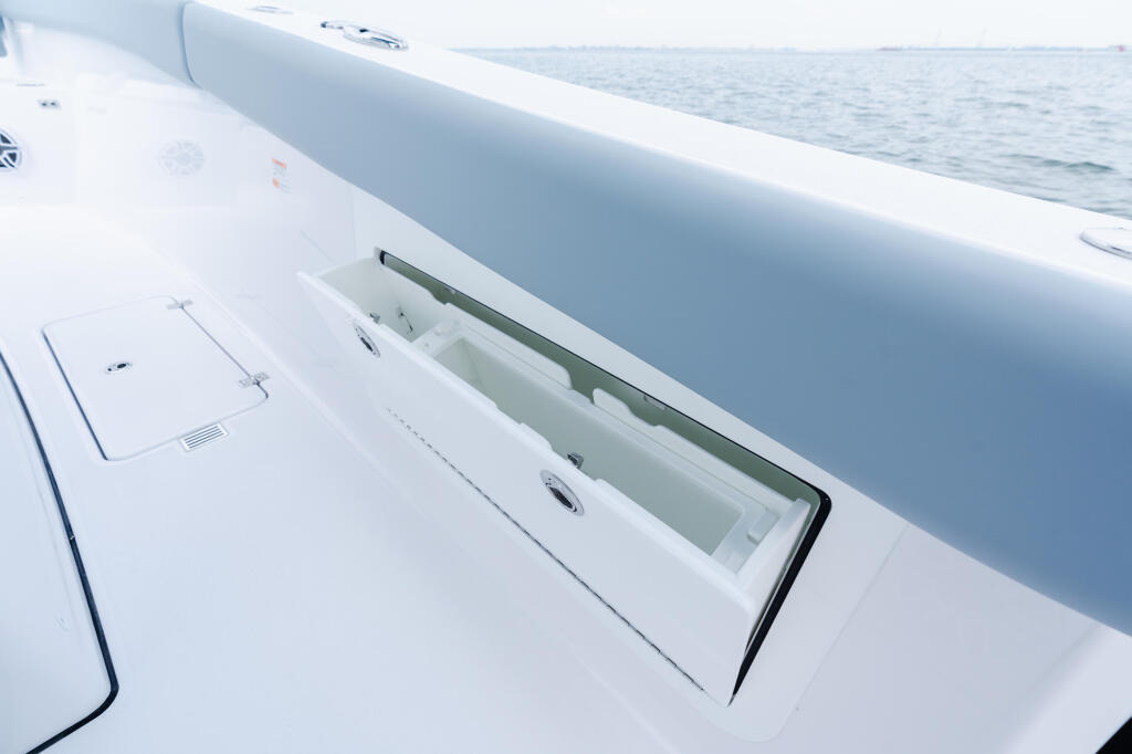 Open livewell storage compartment on boat gunwale with ocean visible beyond