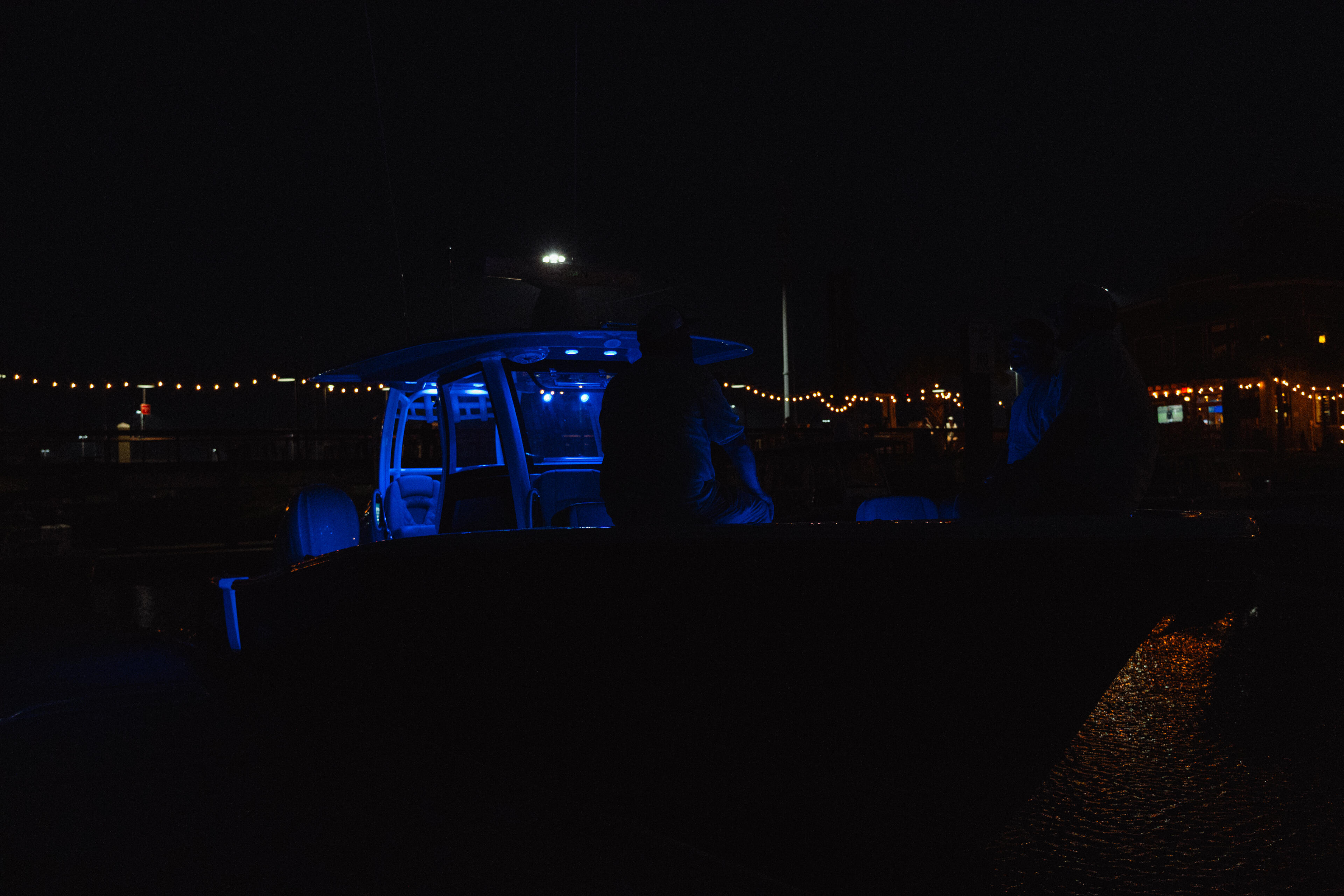 Boat illuminated by blue LED lighting at night in a marina setting