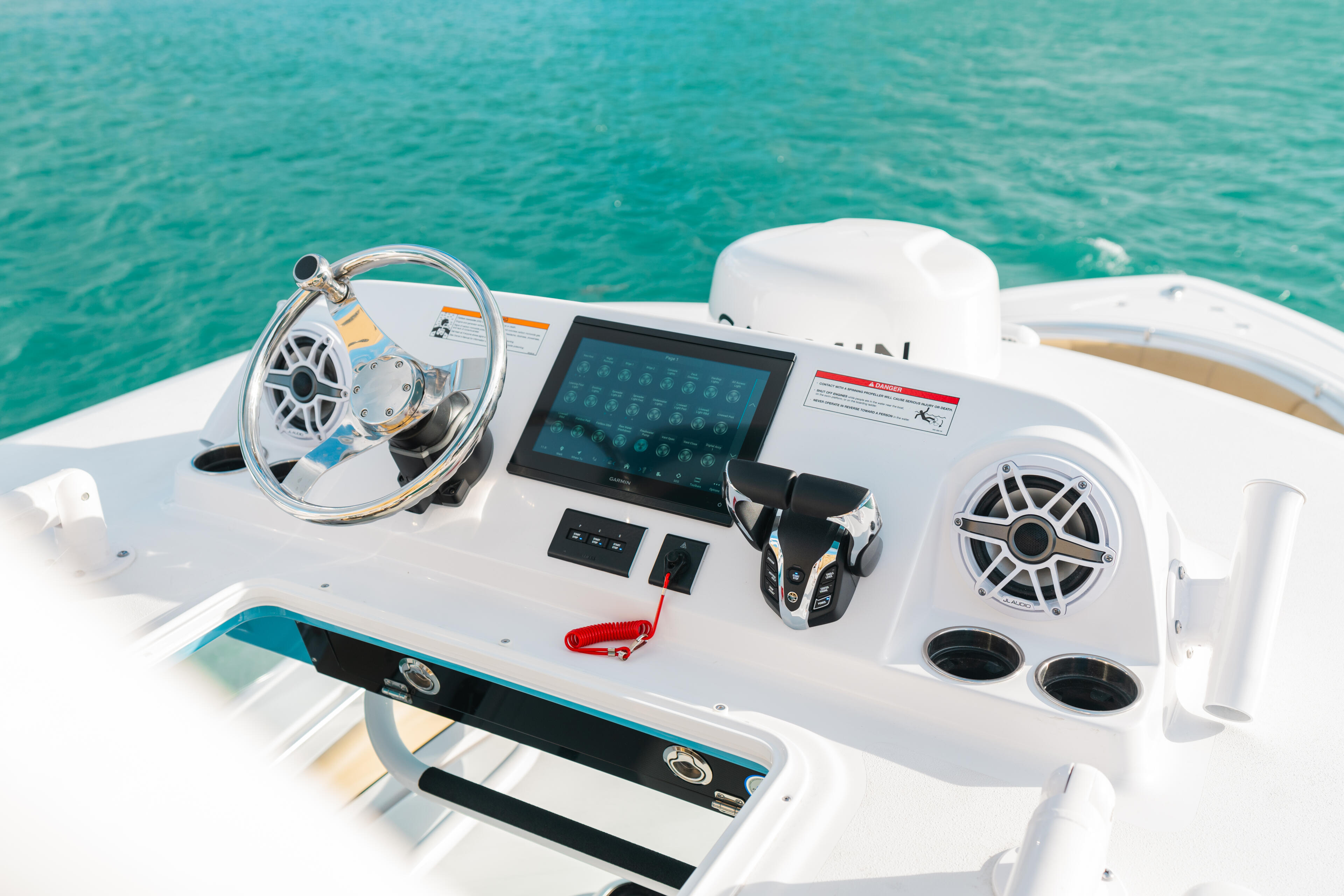 Helm station of center console boat with steering wheel, touchscreen display, and marine electronics overlooking turquoise water