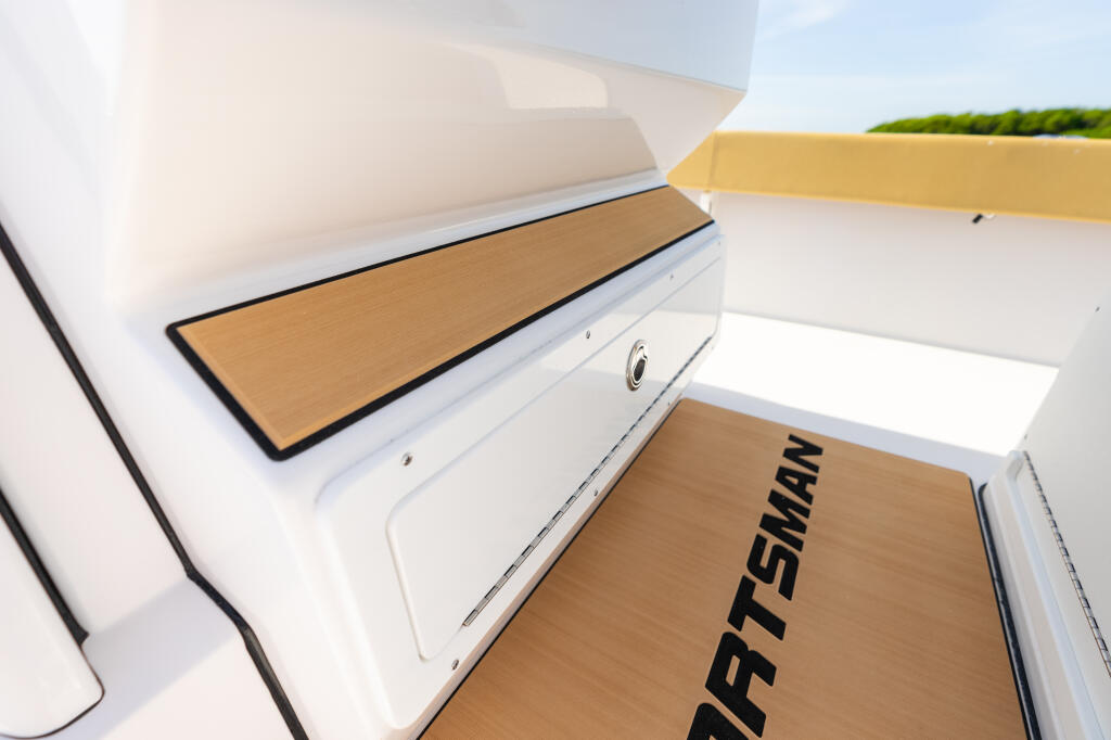 Close-up of boat console footrest with teak wood padding and storage compartment