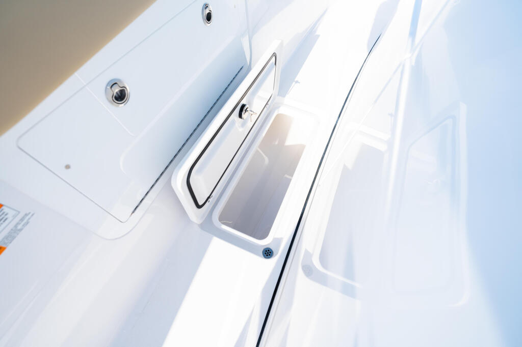 Open gunnel storage compartments with ventilation ports on white boat hull