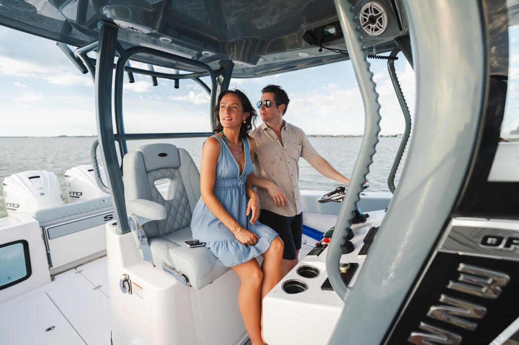 Couple relaxing under the hard-top canopy of a center console boat on calm water