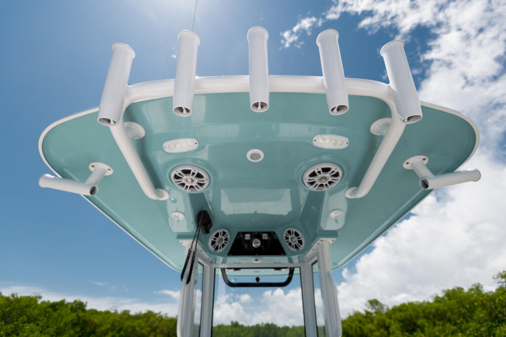 Overhead view of boat's hardtop with white antennas, vents, and speakers against blue sky