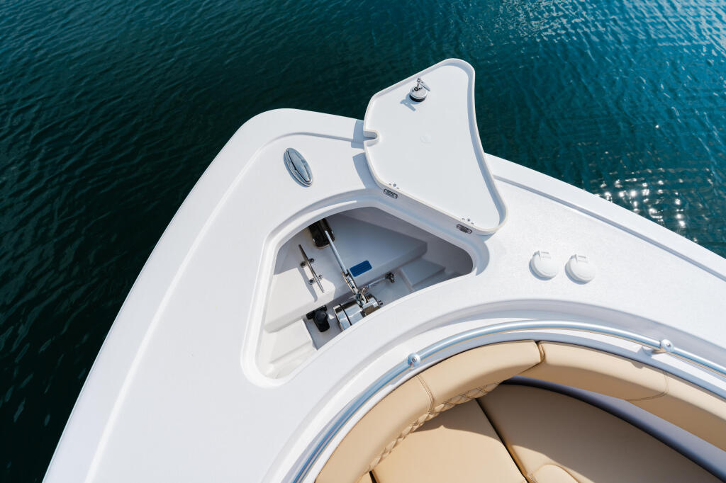 Overhead view of boat's white hardtop cabin with open hatch, steering wheel visible inside, tan seating below, on turquoise water