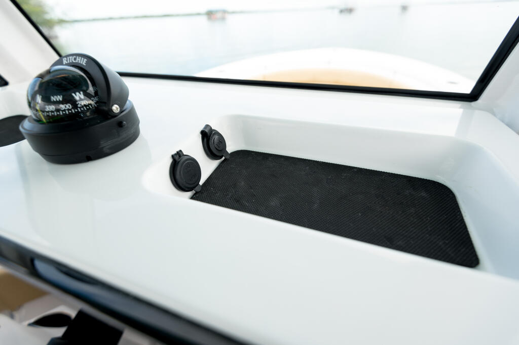 Helm console with Ritchie compass, speakers, and padded storage compartment with black mat
