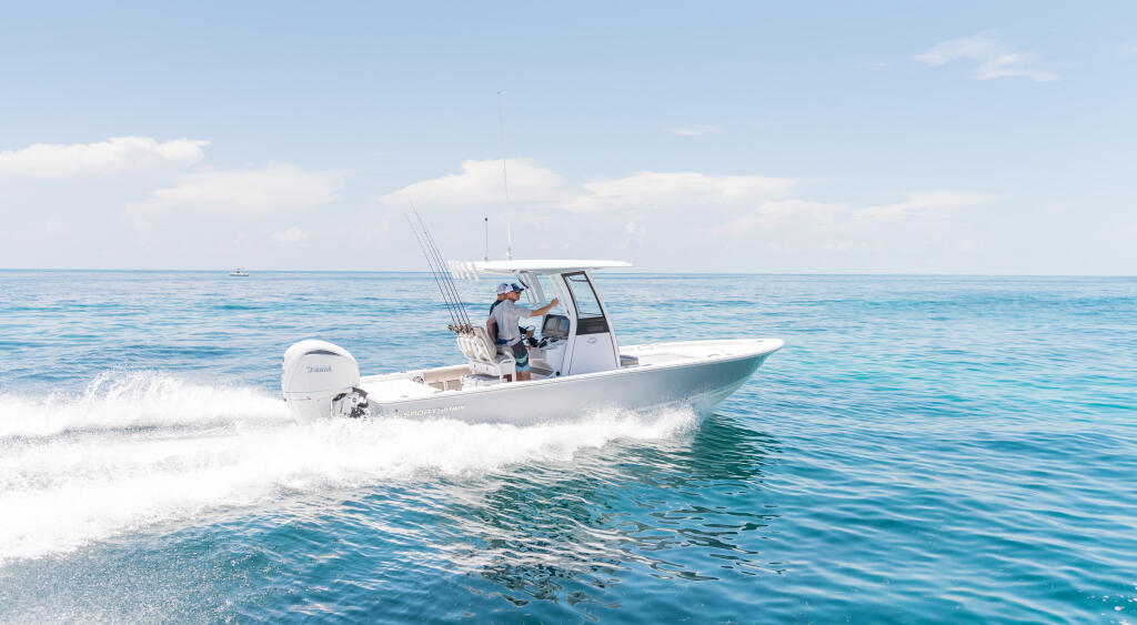 Fishing boat with angler at the helm approaching the beach in clear turquoise waters