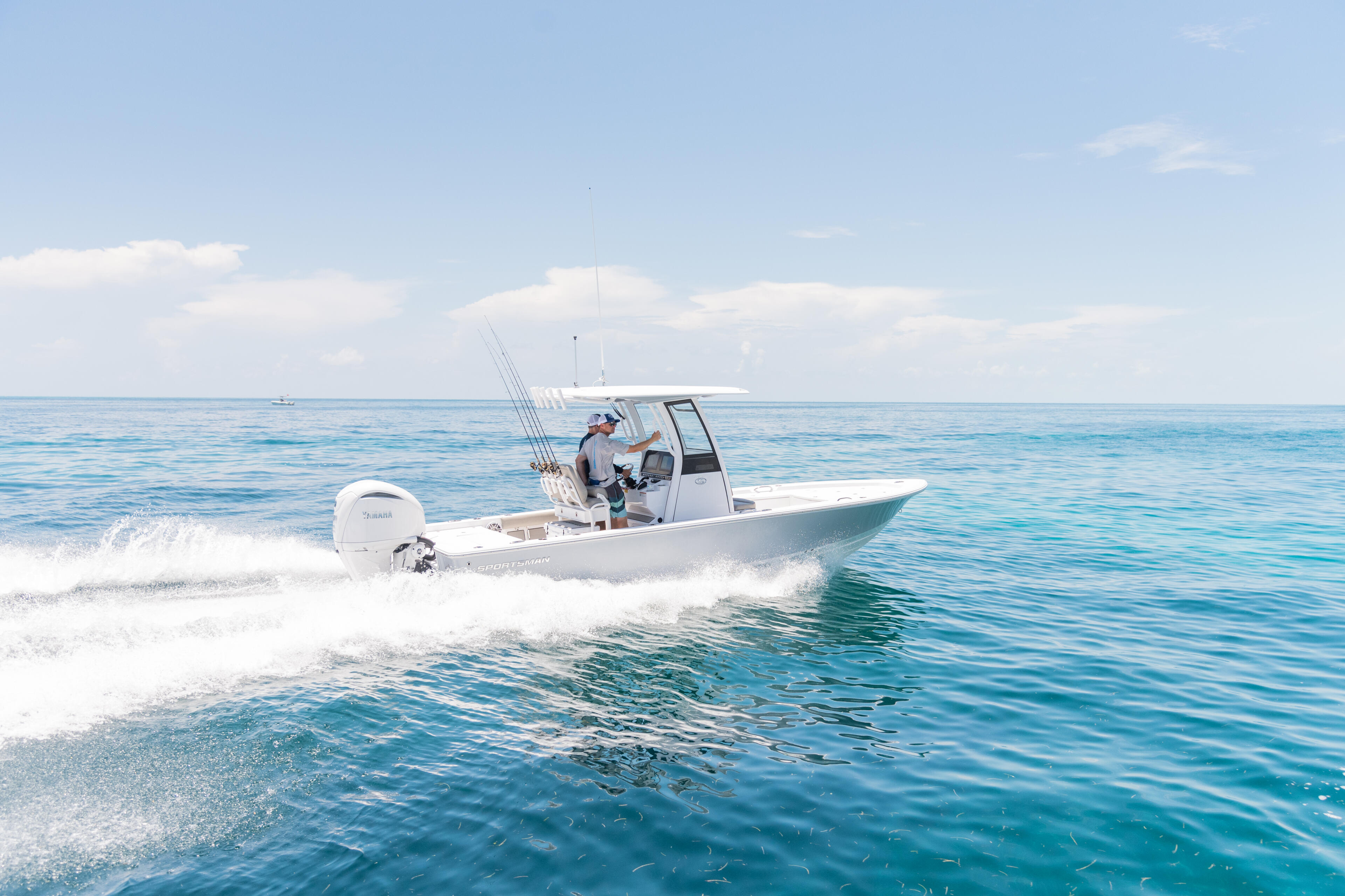 Fishing boat with angler at the helm approaching the beach in clear turquoise waters