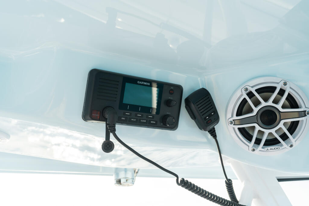 Garmin VHF radio with GPS and JL Audio speaker mounted on boat hardtop ceiling