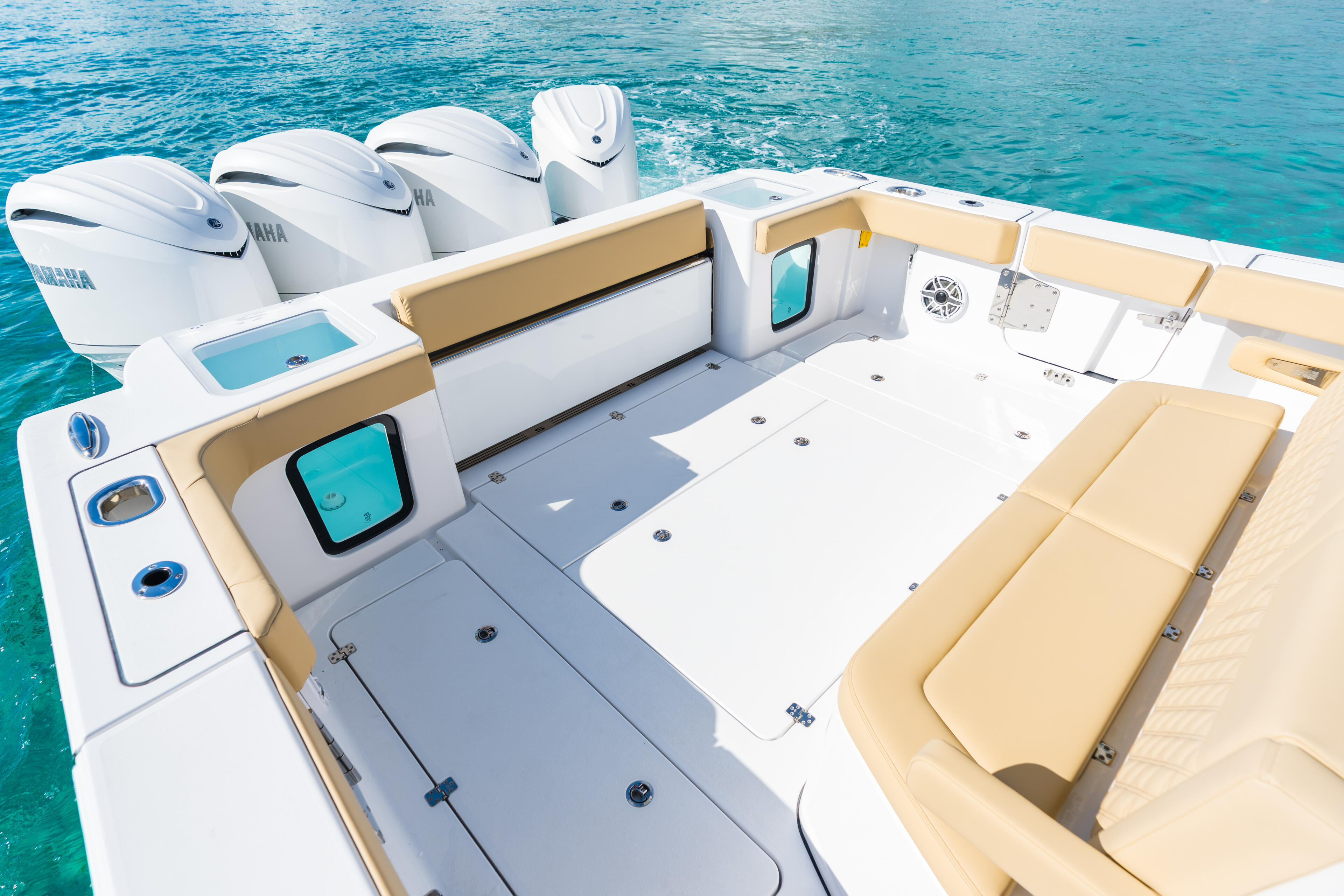 Spacious open fishing boat deck with tan seating, helm controls, three Yamaha engines, and turquoise water