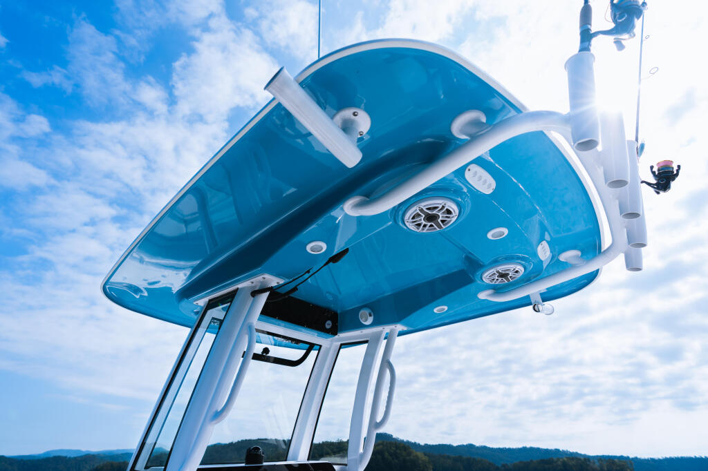 Upward view of a blue center console boat's hard-top with integrated lighting and white frame against bright sky