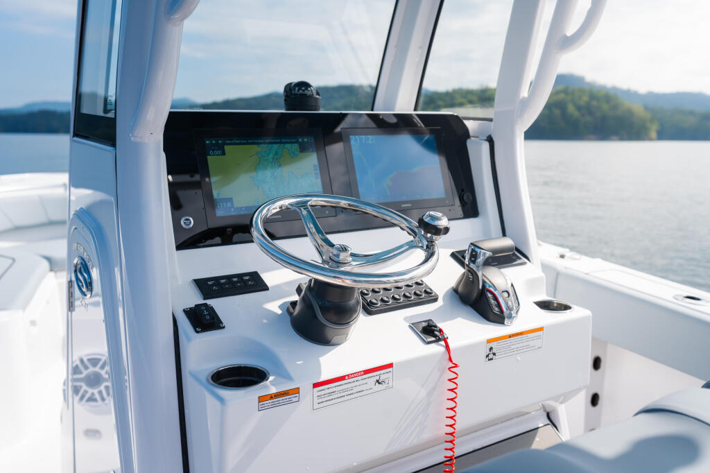 Helm station with SeaStar tilt steering wheel, dual monitors, and control panel overlooking a scenic lake