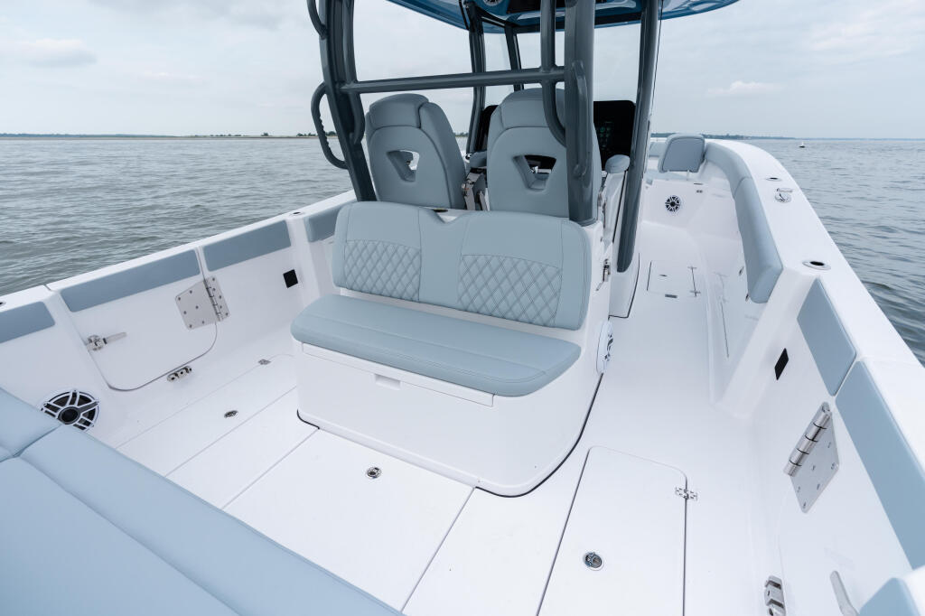Center console fishing boat with gray upholstered seating and hard-top canopy on calm open water