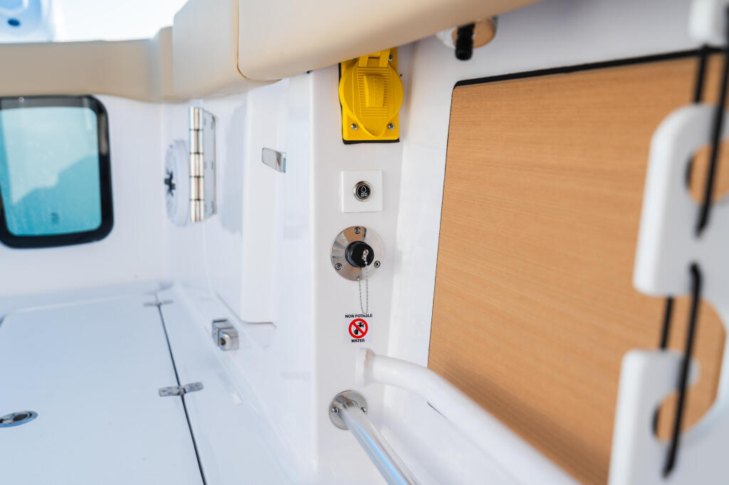 Cabin interior showing white wall panel with yellow light fixture, controls, and wooden cabinetry detail
