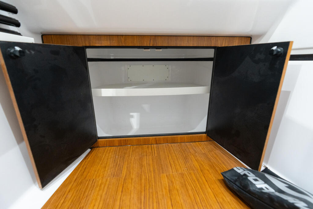 Open cabin with teak wood flooring, black panel doors, and white headliner interior storage