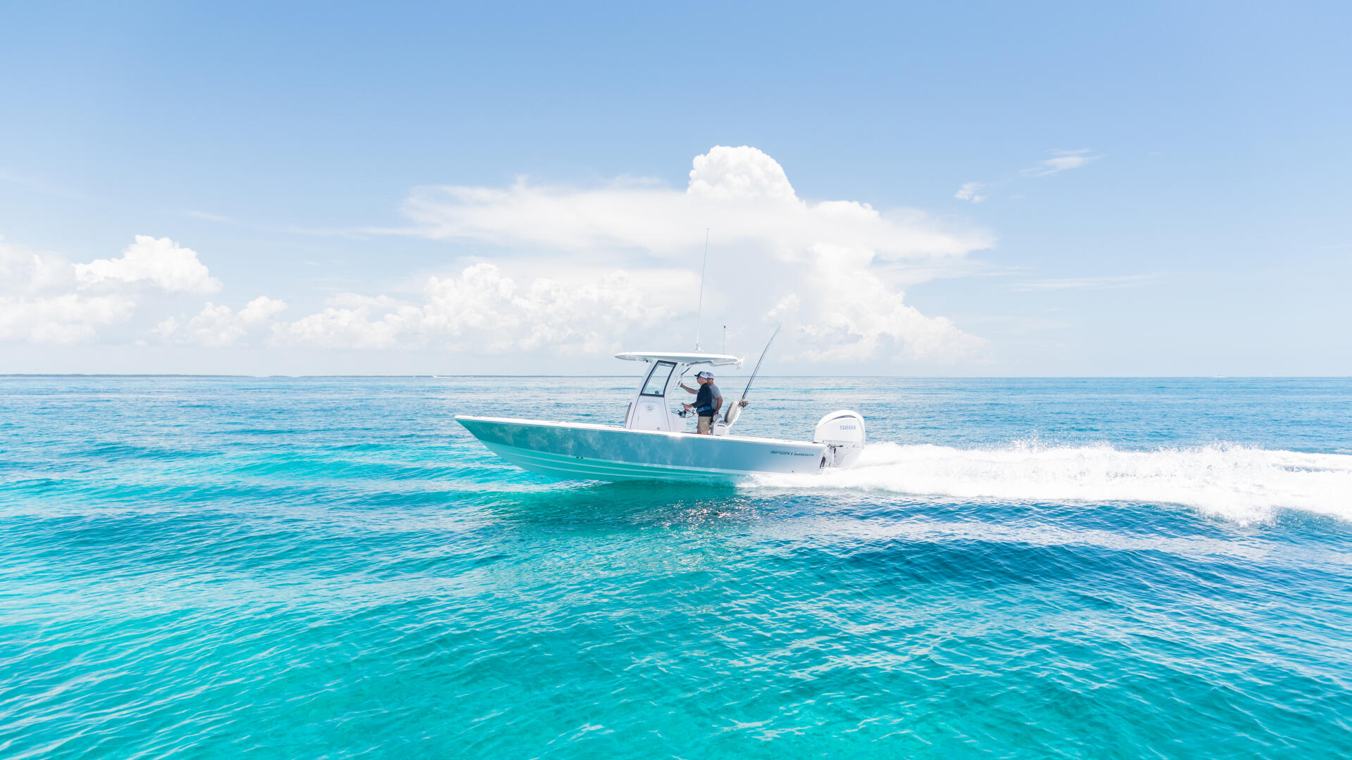 Turquoise water with angler fishing from a running center console boat near the beach