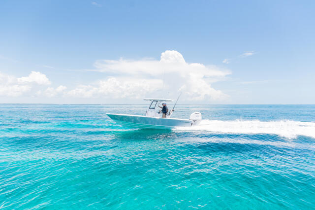 Turquoise water with angler fishing from a running center console boat near the beach
