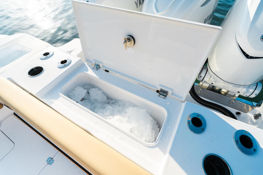 Open cooler filled with ice next to deck hardware and ventilation ports on boat