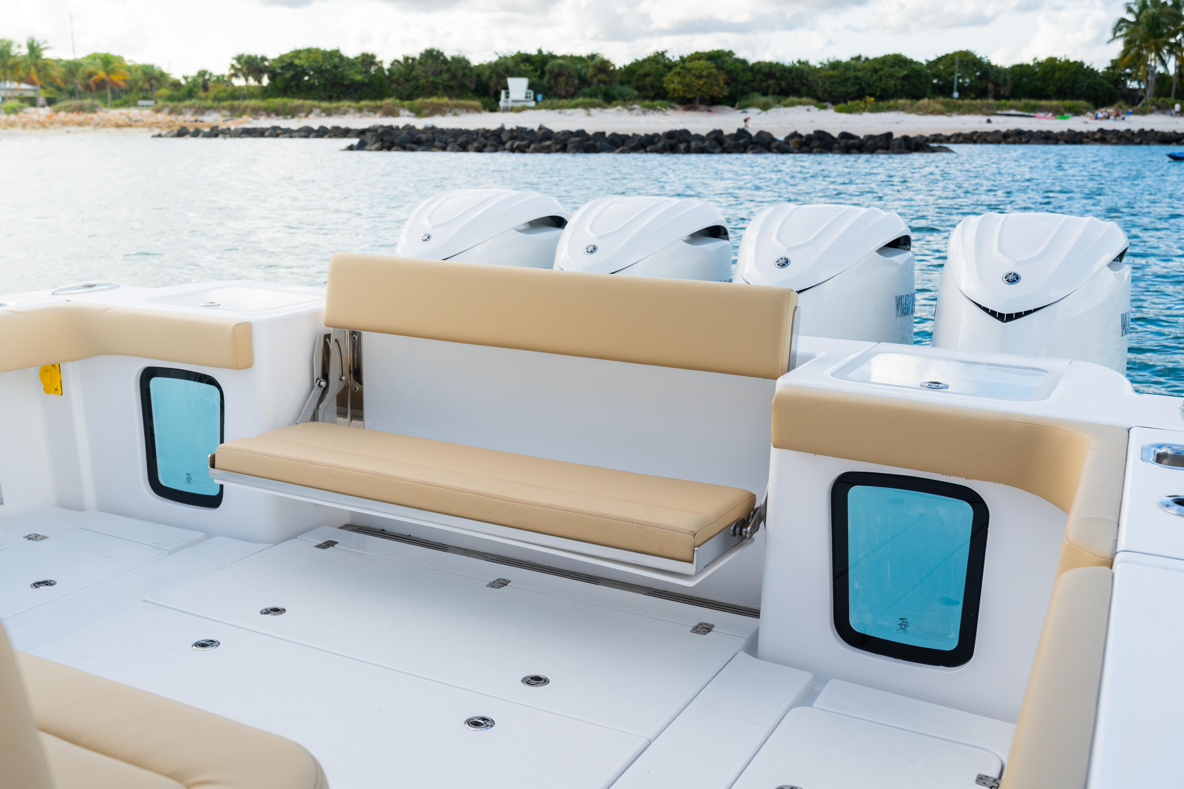 Boat's open cabin with cream and white seating, windows, and four outboard engines visible in background at dock