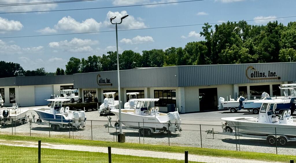 Collins Inc. boat dealership in Smithfield displaying multiple fishing boats on trailers and in showroom bays
