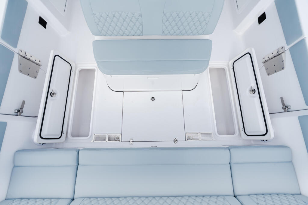 Overhead view of a boat cabin interior with light blue upholstered seating and white storage compartments