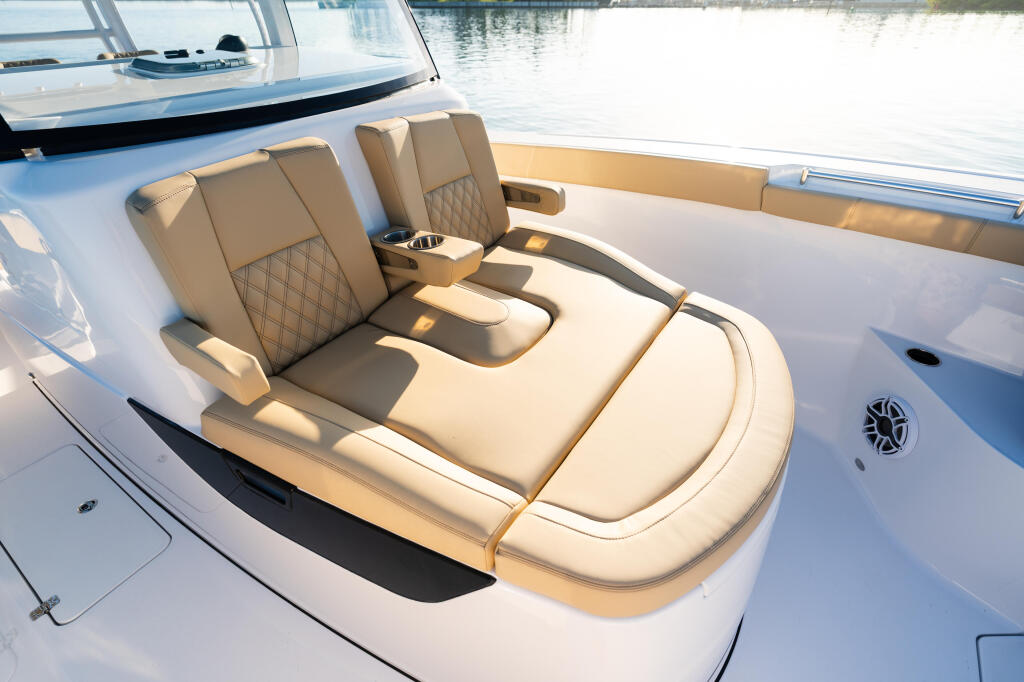 Tan quilted captain and co-captain seating with cupholder in the open bow of a white boat docked at a marina