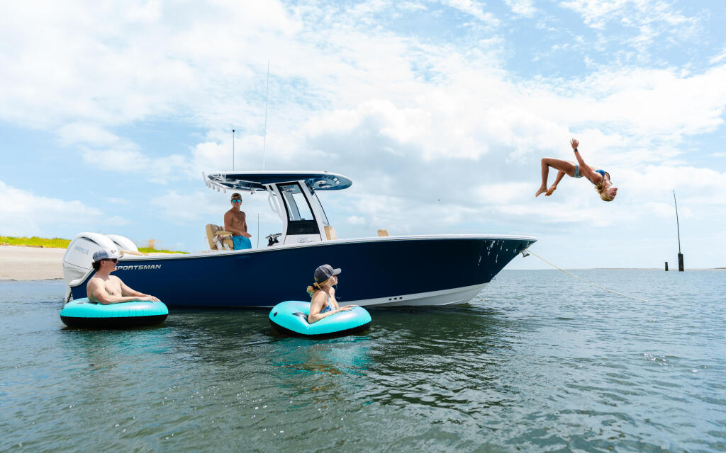 Couple and children enjoying a sandbar day with a blue center console boat, swimming and relaxing in shallow turquoise water