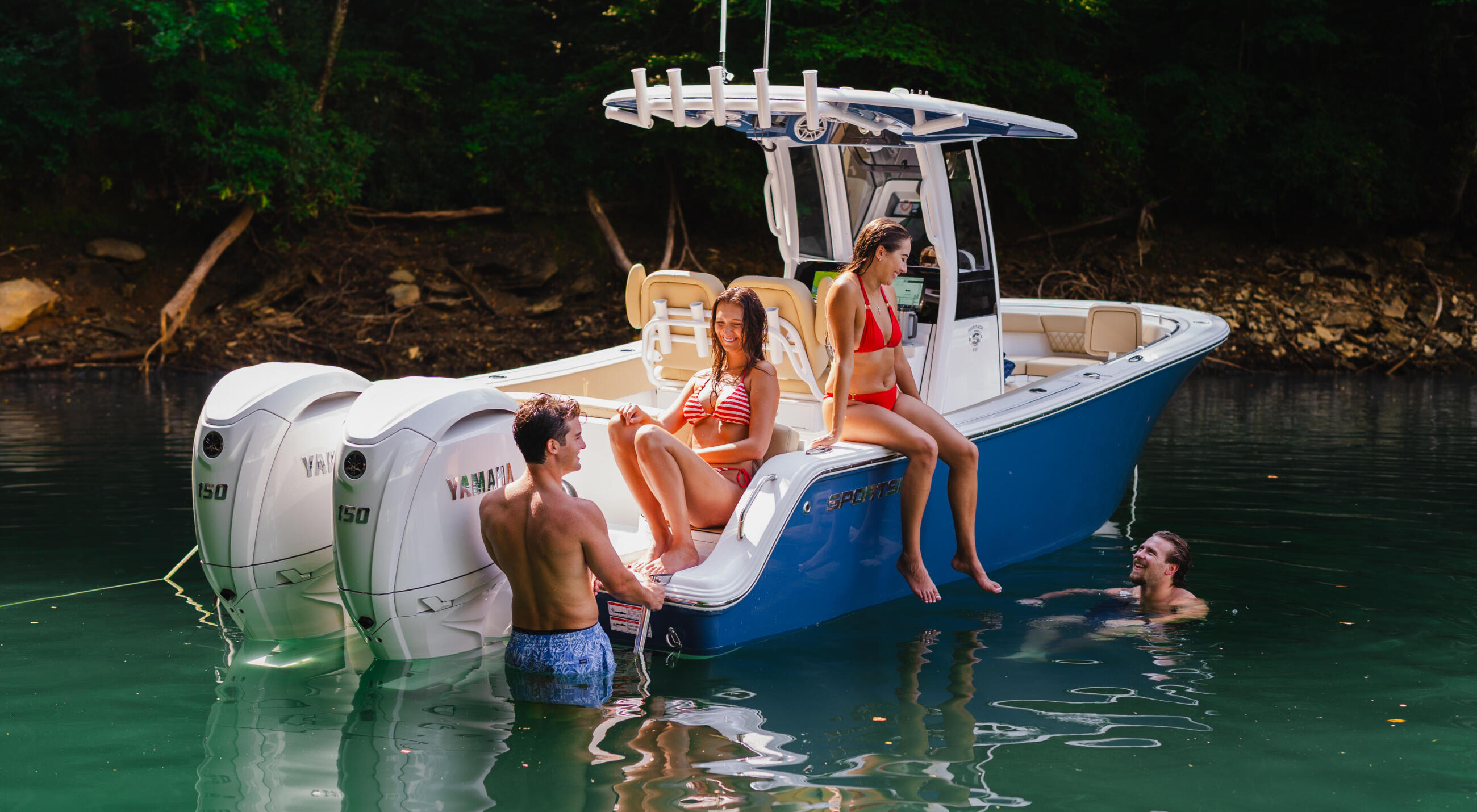 Couples and friends swimming and relaxing around a blue and white center console boat in crystal clear turquoise water