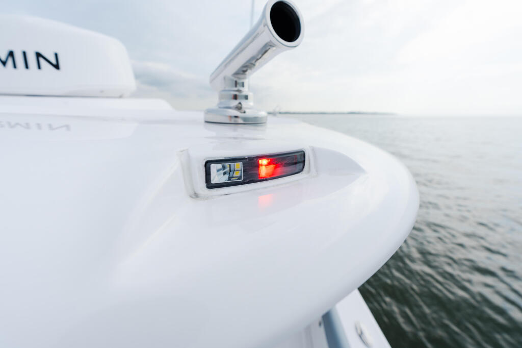 Boat running lights and navigation equipment mounted on white helm console with GPS radar dome visible above