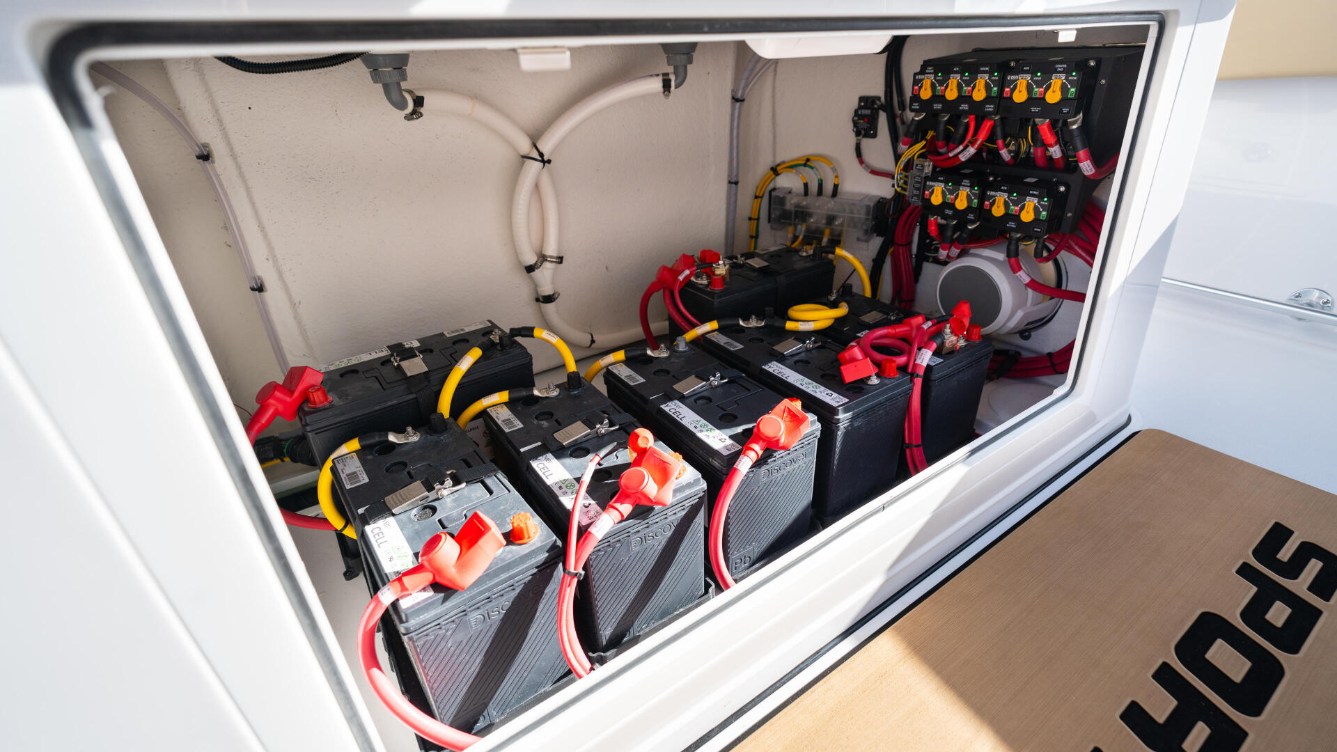 Open engine compartment showing multiple batteries with red and yellow cable connections and electrical panel