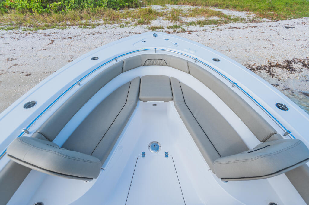Bow seating with gray bolsters and blue accents on a center console boat beached on sand