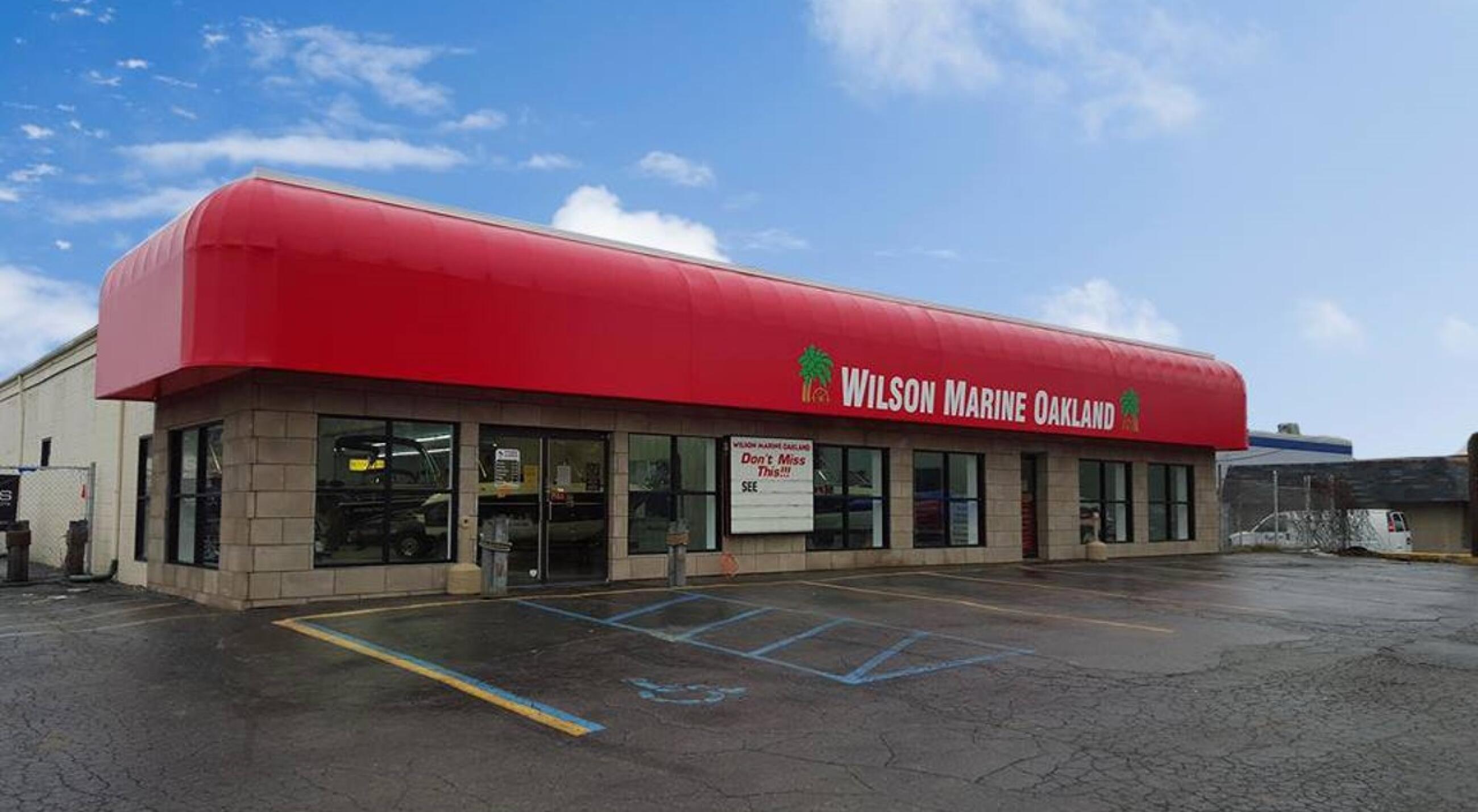 Wilson Marine Oakland storefront with red awning and glass doors in Commerce Township parking lot under blue sky