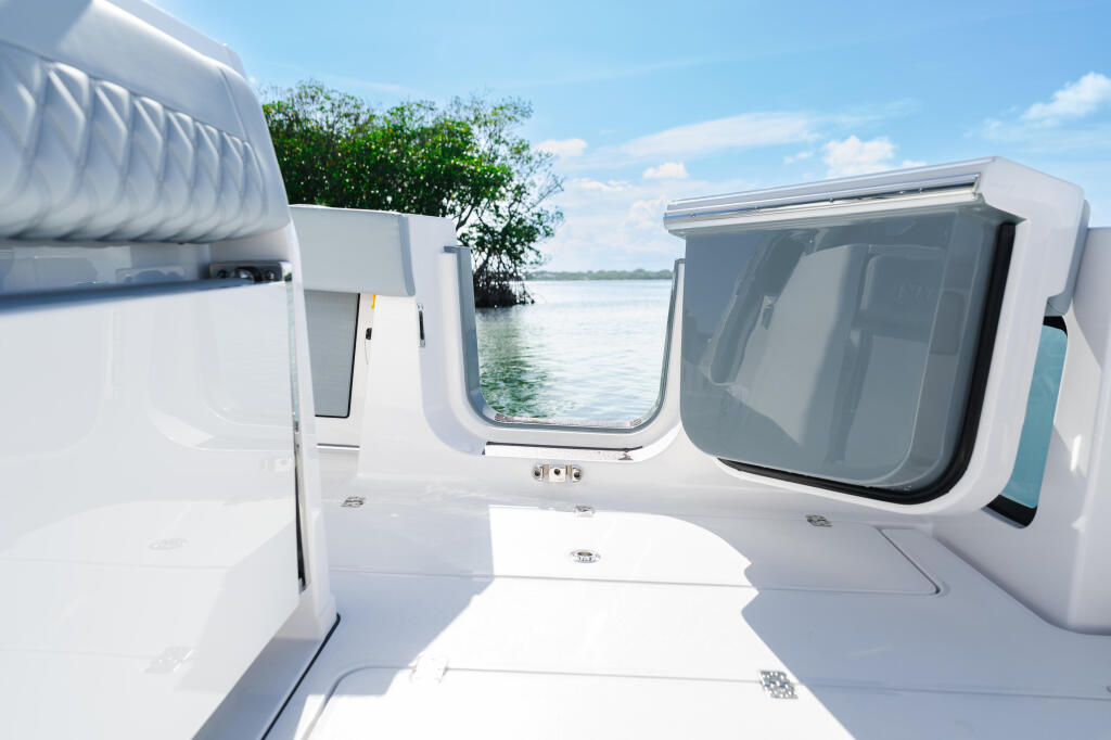 Bright cabin interior with multiple windows overlooking mangrove shoreline and calm water