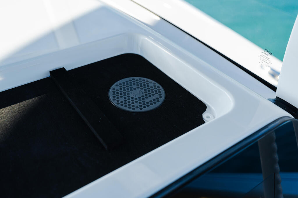 Open boat livewell with perforated drain cover and black interior mat in bright sunlight