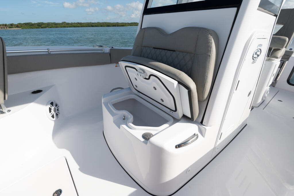 Open center console cockpit with gray quilted helm seat, white cooler, and water views across the bow