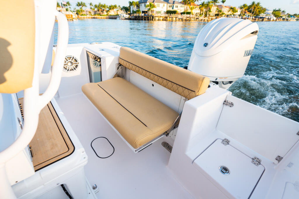 Rear seating area with tan cushioned seats and white hardtop on center console boat near waterfront homes