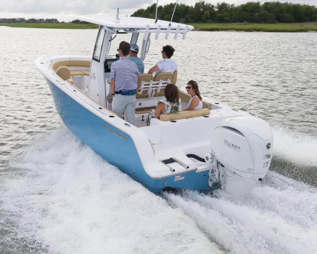 Group of friends cruising in a center console boat through shallow beach waters