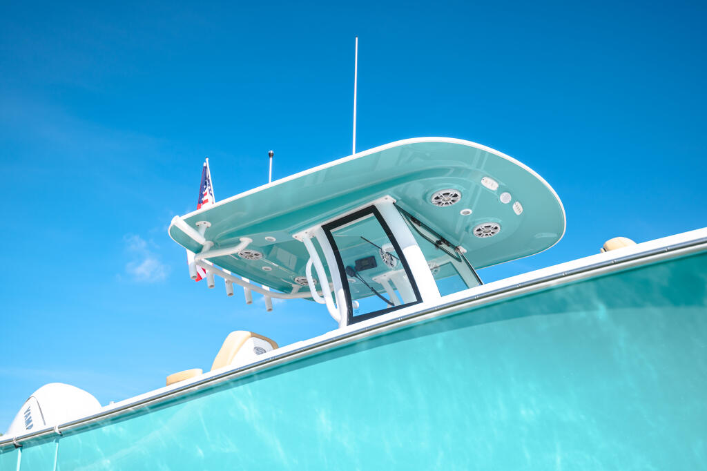 Close-up of a turquoise center console boat's hard-top with integrated lighting and tinted windshield against clear blue sky