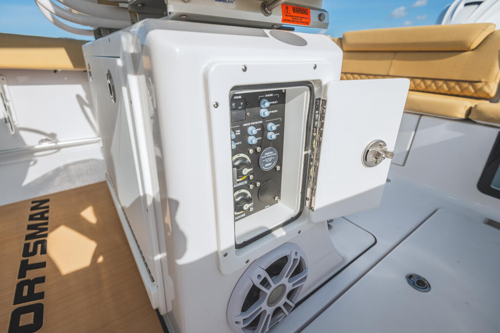 Open electrical panel with switches and controls mounted on white console, tan seating visible